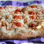 Focaccia de casă coaptă, cu roșii cherry și ulei de măsline, așezată pe un prosop